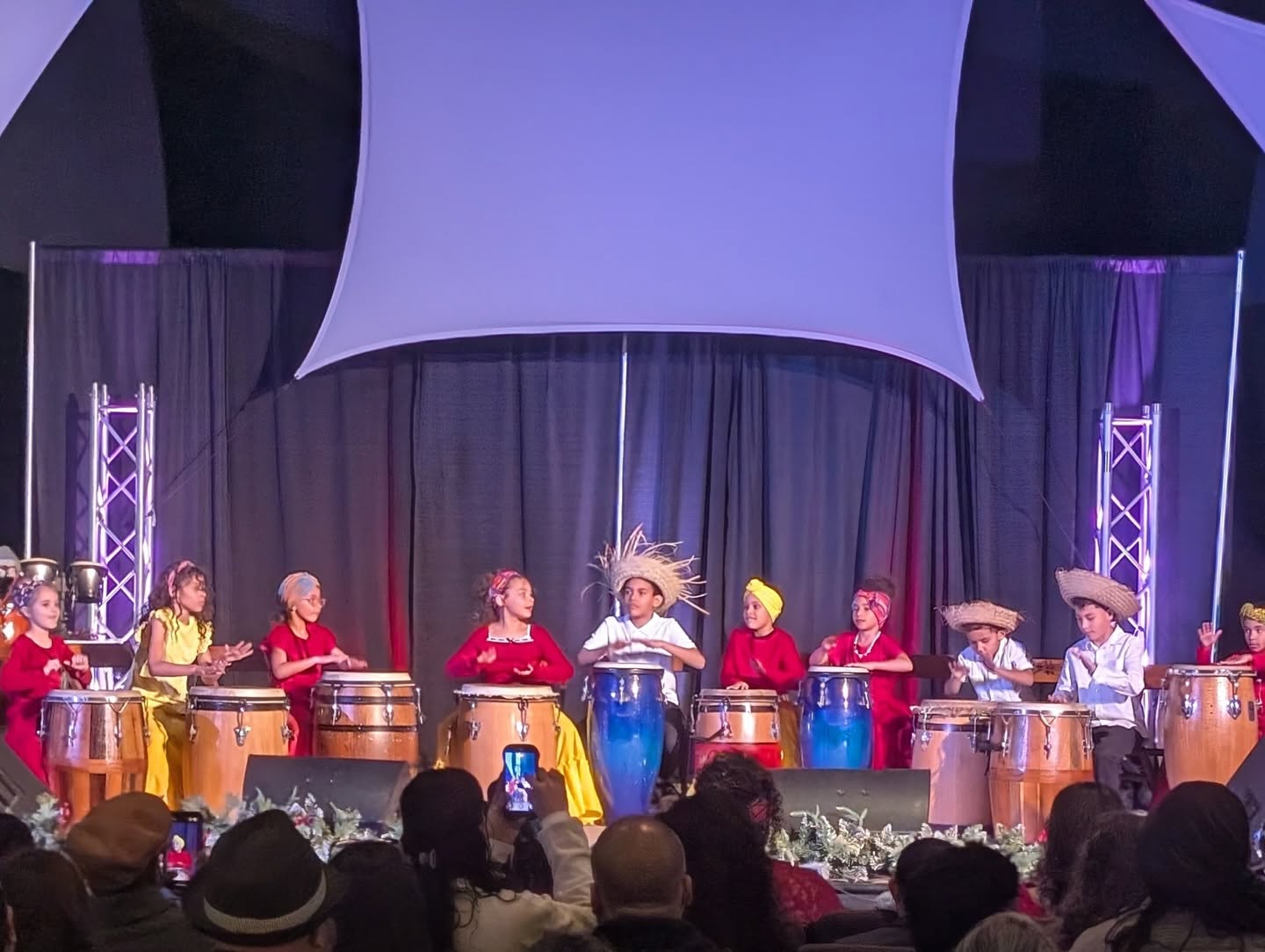 Family members clapping and singing together at a cultural event / Familias cantando y aplaudiendo juntas en un evento cultural