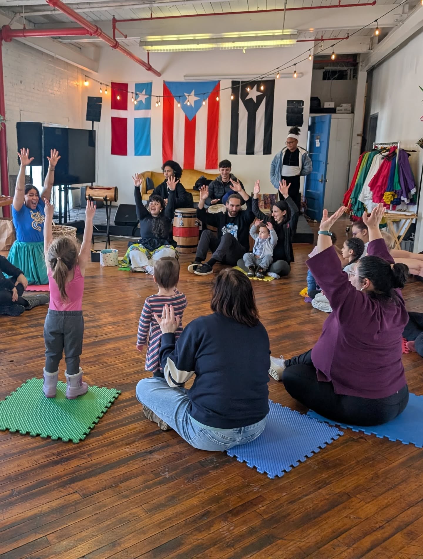 Baby Bomba class — parents and toddlers in a drum circle at El Batey / Clase de Baby Bomba — familias y niños pequeños en círculo de tambores